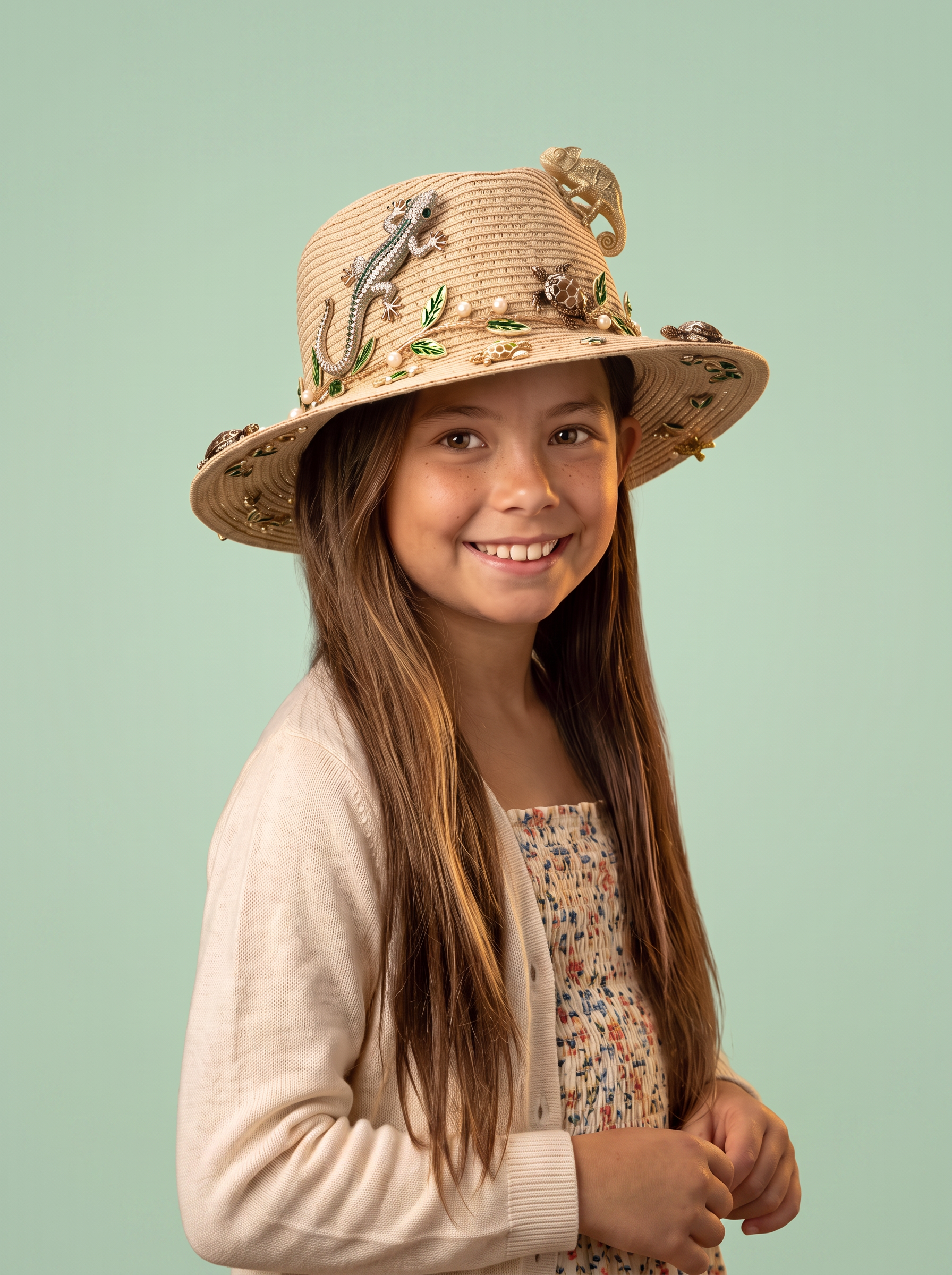 Francesca wearing the Little Gecko hat with a jewelled gecko climbing the crown, a gold chameleon, turtles, green enamel leaves and pearls