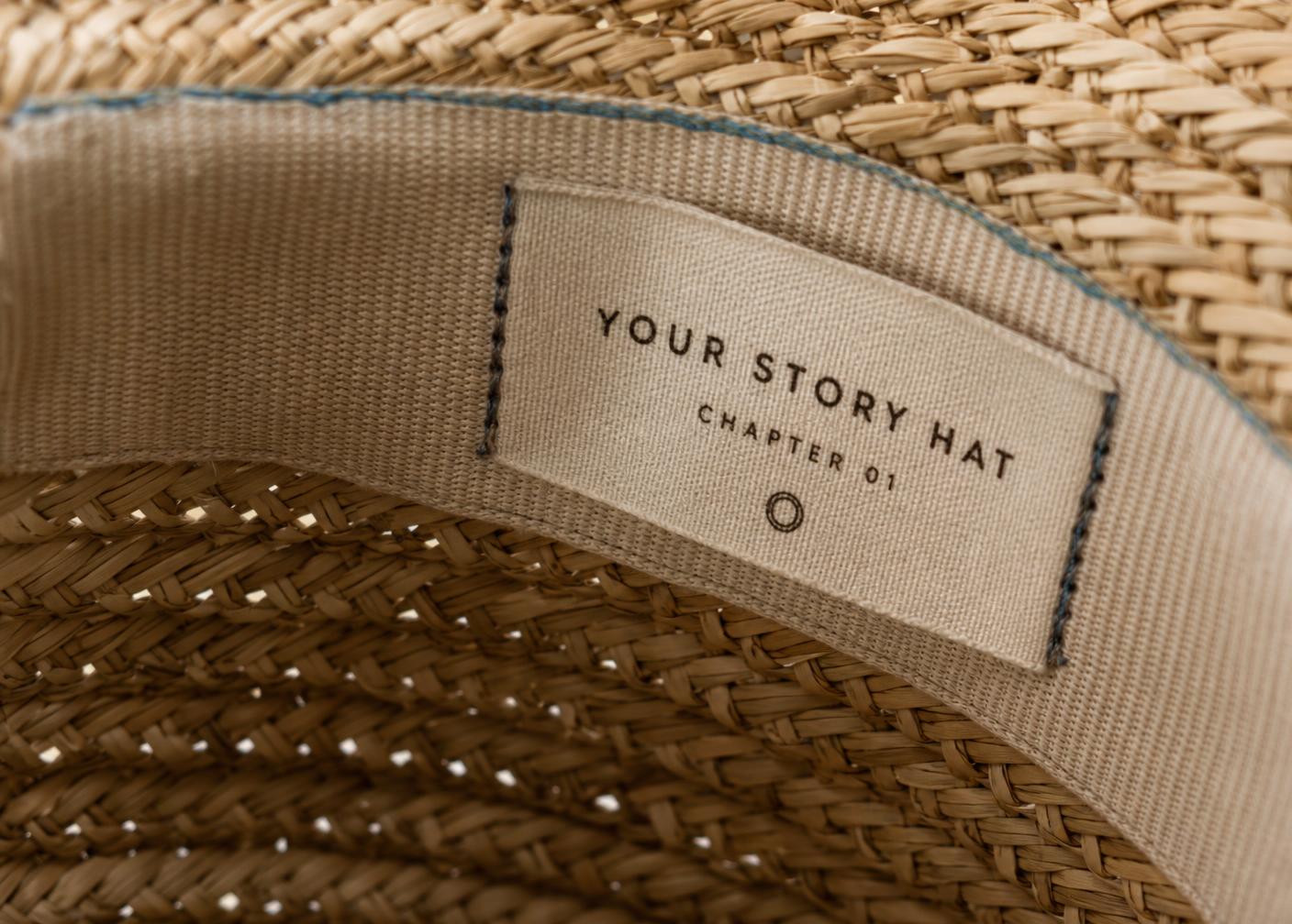 Woven Your Story Hat label reading Chapter 01 stitched inside the sweatband of a straw hat